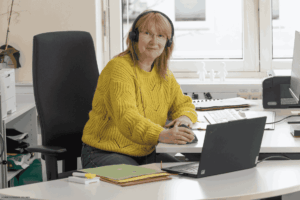 Frau mit Headset sitzt am PC